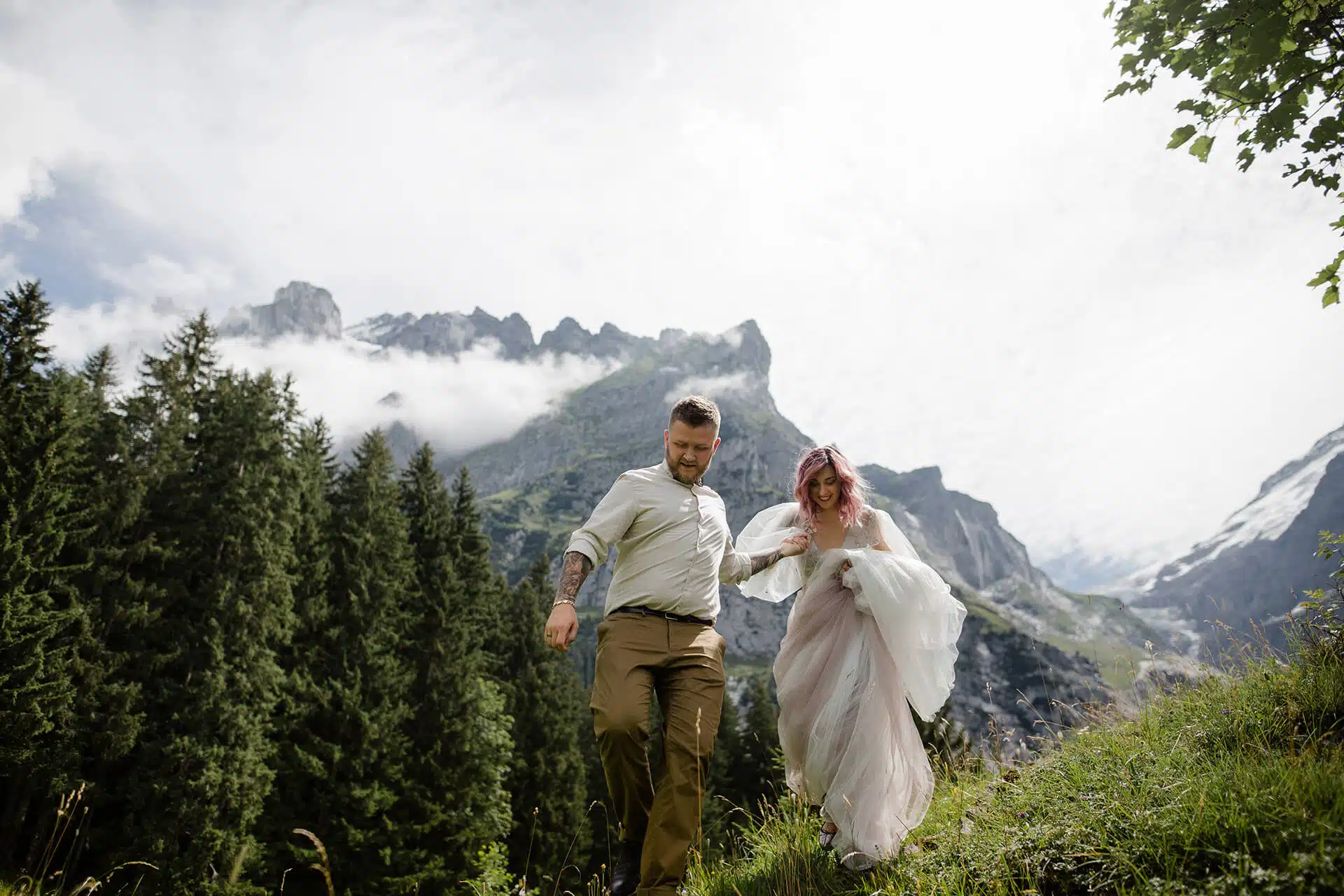 Hochzeitspaar steht allein auf einer Bergwiese bei Sonnenaufgang